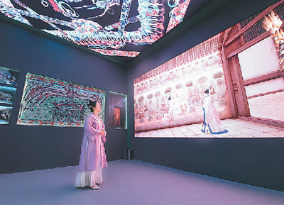 第十九屆中國（深圳）國際文化產(chǎn)業(yè)博覽交易會設(shè)立了“數(shù)字中國——AI時代的文化創(chuàng)新”主題展區(qū)。一批大數(shù)據(jù)、人工智能等技術(shù)應(yīng)用文化企業(yè)參展。數(shù)字化助力中華傳統(tǒng)文化“活”起來，也為現(xiàn)場觀眾帶來了新鮮的觀展體驗。   圖為一名身著傳統(tǒng)服飾的觀眾在文博會甘肅展臺觀看數(shù)字敦煌展覽。   新華社記者 梁 旭攝