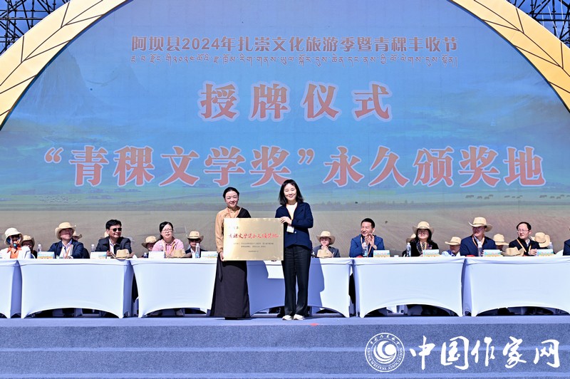 陳亞軍主編代表《民族文學(xué)》向阿壩縣授牌，紅梅部長接牌。